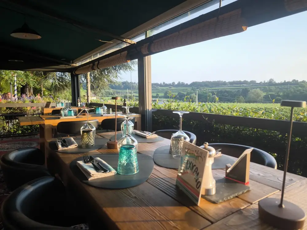 Outdoor table at Osteria Metti in Incaffi with vineyards in the background
